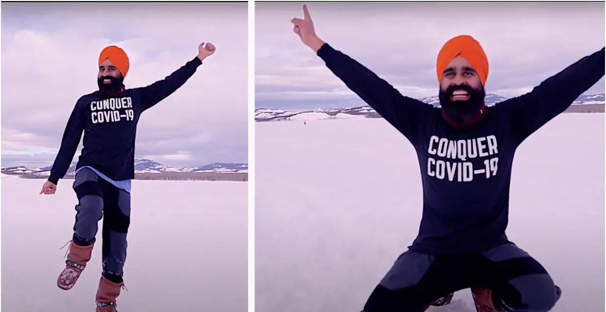 man taking selfie in orange turban and black outfit to celebrate covid 19 vaccination with a black shirt that reads Conquer Covid-19