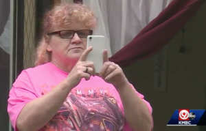 Gina Gibson stops to take a picture as the volunteers fix her home, screenshot via KMBC News