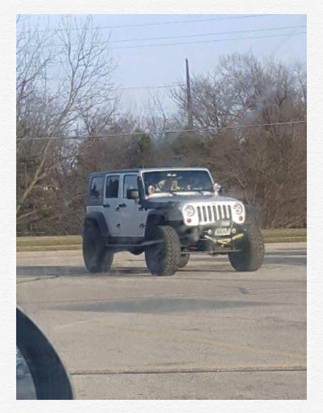 A Silver Jeep Wrangler sits isolated in the parking lot